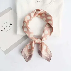 Detailed shot of pink polka dot silk scarf, elegant satin texture, stylish neck accessory.
