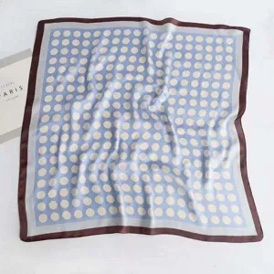 Detailed view of blue polka dot silk scarf with brown border, elegant accessory for women.
