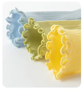Detailaufnahme von Kindersocken mit süßem Rüschenrand und atmungsaktivem Pastellstrick.