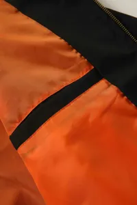Close-up detail of a stylish men's bomber jacket featuring vibrant orange lining and black contrast.