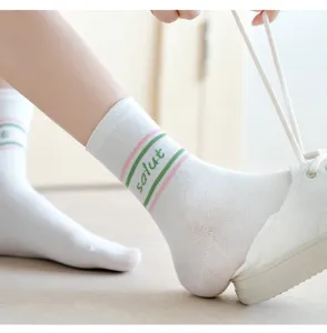 Nahaufnahme von weißen Waden Socken mit rosa grünen Streifen und gestricktem Text für Frauen.