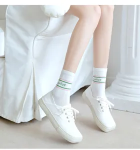 Weiße Sneaker und süße gestreifte Socken für Damen lässige Alltagsschuhe und Strümpfe.