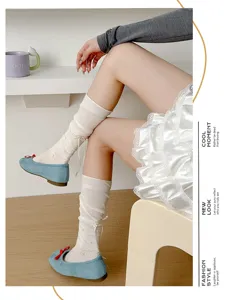 Close-up detail shot of sweet floral long socks with bow ribbons paired with blue flats.