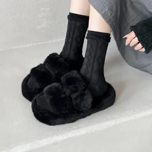 Stilvolle schwarze flauschige Pantoletten kombiniert mit gemusterten Socken für gemütlichen Alltag.