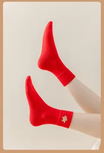 Detailansicht roter Damen-Mittelsocken mit niedlicher Cartoon-Stickerei aus weichem Stoff.