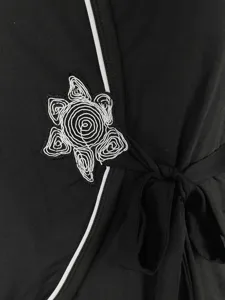 Detalle en primer plano de una bata de dormir negra de mujer con bordado blanco elegante.