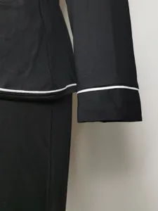 Vista detallada de parte superior de pijama negro de manga larga con ribetes blancos.