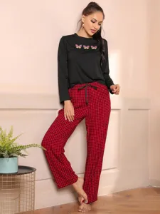 Detailed view of the women's long-sleeve pajama top with cute butterfly prints and cozy plaid pants.