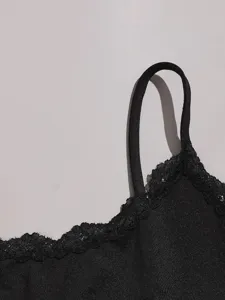 Detailed close-up of a black camisole strap and delicate lace trim on sleepwear apparel.