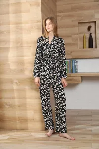 Detailansicht des floralen Langarm-Pyjama-Sets vor gemütlichem Holzzimmer-Hintergrund.