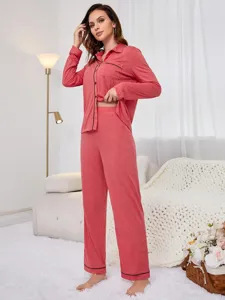 Detail view of women long sleeve pajama set with black trim in cozy indoor bedroom scene.