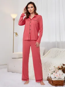 Detailed view of women's long-sleeve button-down pajama set in coral with black piping.