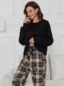 Detail view of women long sleeve pajama set, black top and plaid floral pants, cozy.