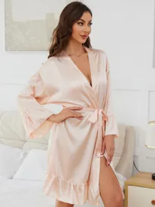 Detail shot of women's silk satin robe featuring ruffle hem and elegant long sleeves in bedroom.