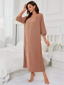 Detailed view of women long sleeve casual lounge dress in solid brown worn by model in bedroom