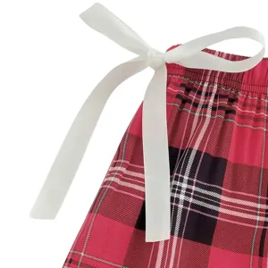 Close-up detail shot of women's plaid lounge pants waistband featuring a white bow ribbon.