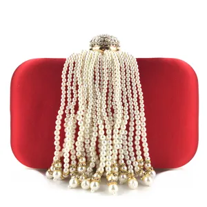 Close-up view of red satin evening bag showcasing cascading pearl tassel strands and crystal clasp.