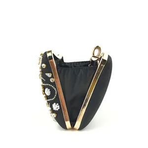 Vue détaillée de la pochette de soirée en satin noir avec cadre doré et broderie strass.