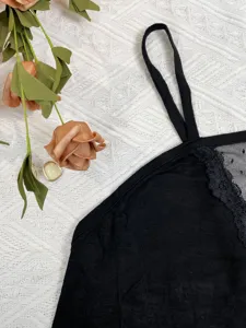 Détail de caraco noir élégant montrant des coutures en dentelle délicate sur tissu texturé.