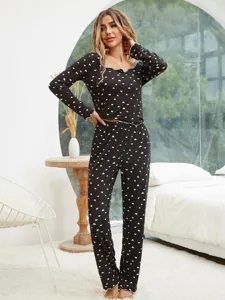Detailed view of women's black long sleeve heart print pajama set in a cozy bedroom.