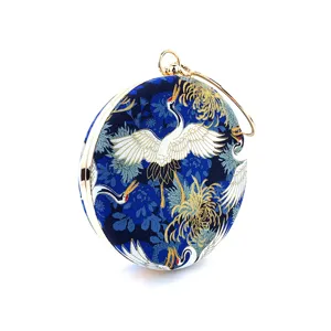 Detailed close-up of round evening clutch bag featuring blue crane print and gold frame.