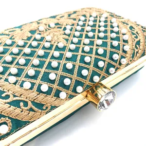 Exquisito detalle de bolso de noche bordado en verde esmeralda con perlas y hilos dorados.
