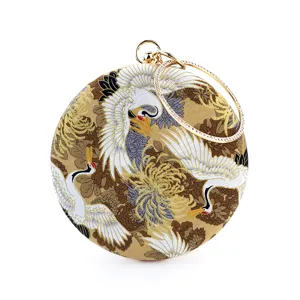 Detailed view of round evening clutch with crane print gold metal frame rhinestone handle.