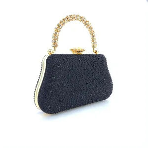 Vue détaillée du sac de soirée noir en strass avec poignée étincelante et fermoir doré.