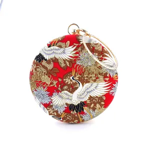 Close-up detail of the exquisite crane and chrysanthemum pattern on the red circular clutch bag.