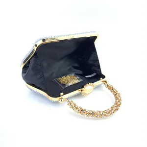 Vue détaillée de la pochette de soirée de luxe en strass avec cadre et poignée dorés.