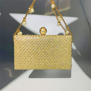 Close-up detail of luxury gold rhinestone evening clutch bag with elegant pearl chain strap.