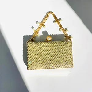 Close-up detail of luxury gold rhinestone evening clutch bag with pearl chain handle.
