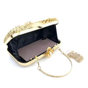 Gold sequin evening clutch bag with pearl flower clasp and chain strap detail view.