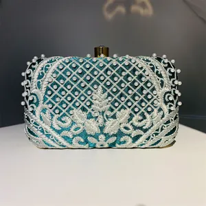 Vista detallada del elegante bolso de noche bordado en verde oscuro con perlas.