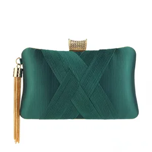 Close-up of dark green satin evening clutch showing pleated fabric design and gold crystal clasp.
