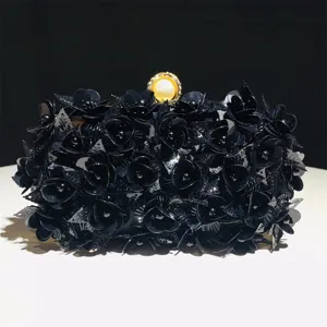 Detail shot of a black sequin floral evening clutch bag with elegant pearl clasp decoration.