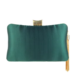 Detailed shot of dark green satin evening clutch bag with elegant gold clasp and tassel accessory.