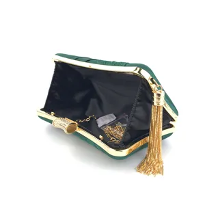 Detailed interior view of dark green satin evening clutch bag with gold chain and tassel.