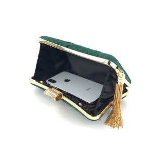 Dark green satin evening clutch bag detail featuring a gold frame, rhinestone clasp, and tassel.