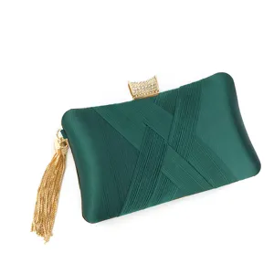 Green satin evening clutch bag detail showing pleated design, crystal clasp and gold tassel.