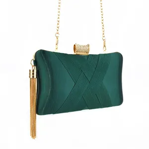 Detailed close-up of dark green pleated satin evening clutch bag with gold chain and tassel.