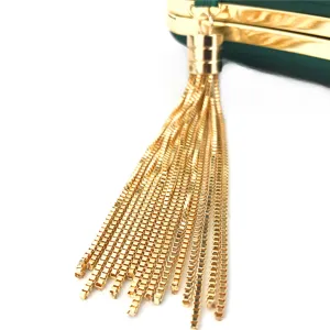 Detailed close-up of elegant green satin evening clutch bag featuring a luxury gold chain tassel charm.