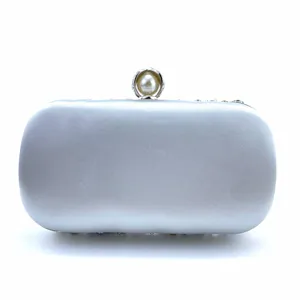 Detailed close-up view of the silver satin evening clutch with an elegant pearl clasp design.