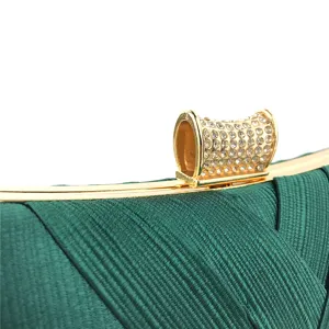 Green satin evening clutch bag detail close-up showcasing elegant rhinestone clasp.