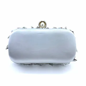 Elegant silver satin evening clutch featuring stunning metallic leaf accents and pearl clasp.