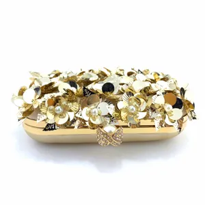 Detailed view of luxury gold sequin evening clutch bag with metallic flower and pearl clasp