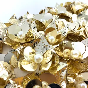 Exquisite sequin clutch bag detail showing handcrafted metallic gold flowers and elegant pearl beads.