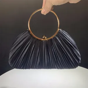 Black pleated satin evening clutch bag detail with luxury gold round metal ring handle.