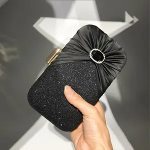 Elegant black evening clutch bag with pleated satin top, sparkling glitter base, and rhinestone decor.