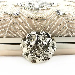 Close-up detail of luxury beaded evening clutch bag with sparkling crystals and floral clasp.